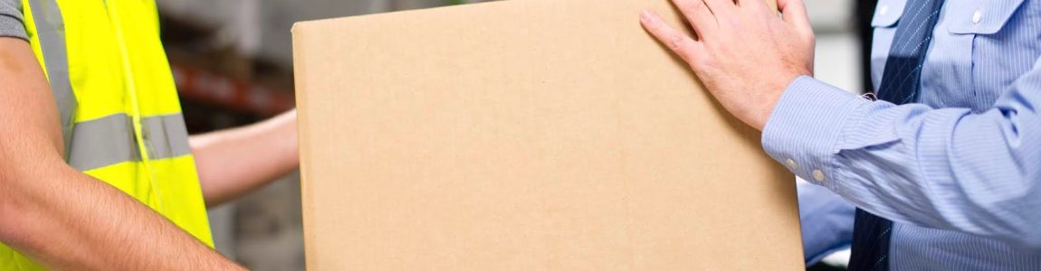 Warehouse worker and manager help each other move a cardboard box.
